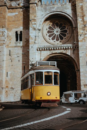 Quaint yellow tram passes directly in front of the Se Cathedral in Lisbon. Lisboa Lissabon Quaint yellow tram passes directly in front of the Se Cathedral in Lisbon. Lisboa Lissabon.